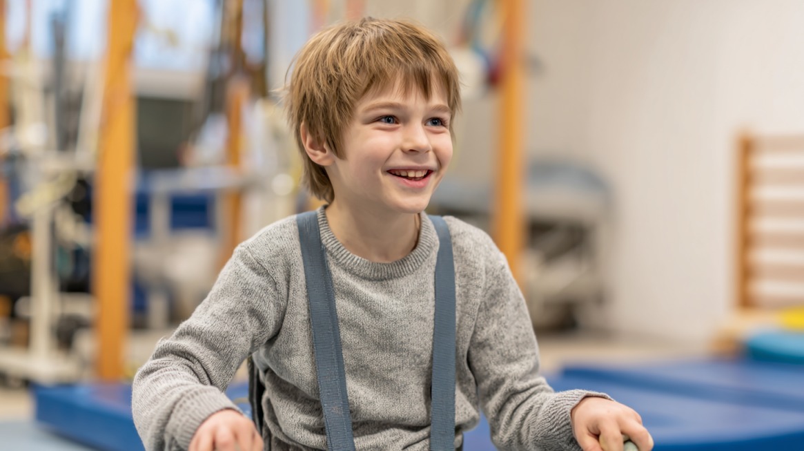Smiling young boy with light brown hair participating in a therapy session indoors