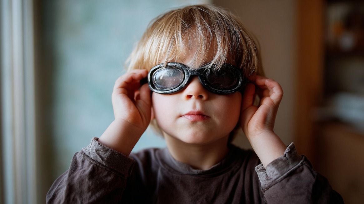 Young child wearing dark goggles while looking forward indoors