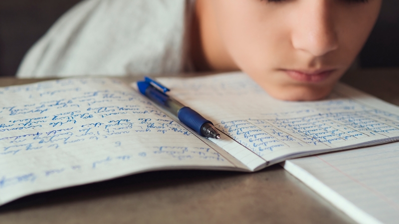 A student concentrates on handwritten notes, reflecting the effort Dyslexic Kids invest in overcoming academic challenges
