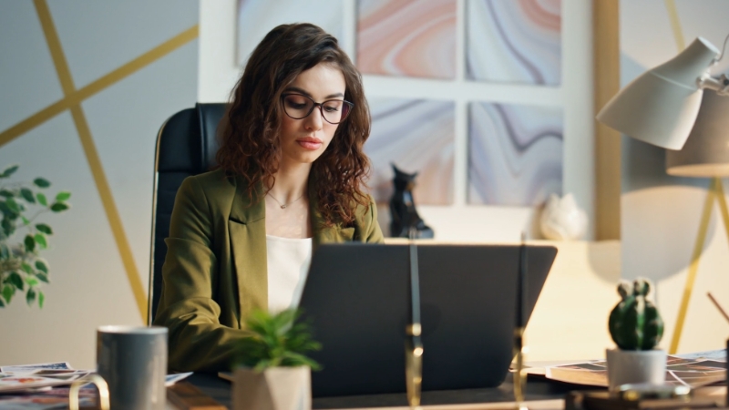 Woman sitting upright at a desk and working on a laptop with proper screen positioning