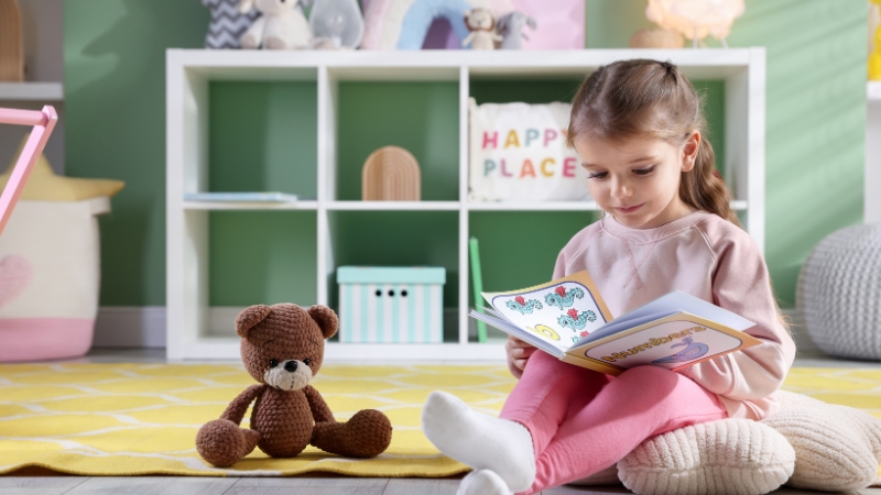 Toddler reads a picture book on the floor to support brain development in toddlers