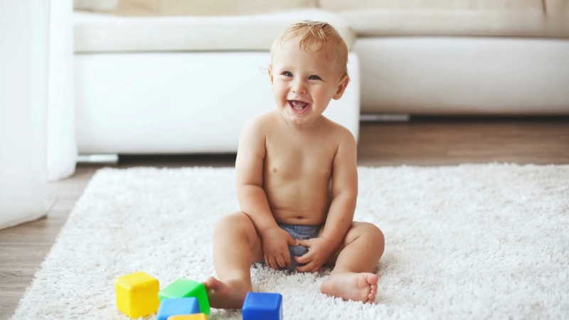 Baby sits on a rug and plays with blocks during 12-month development stage