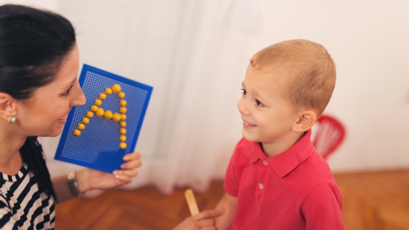 2-year-old not talking child working with a speech therapist using a letter board