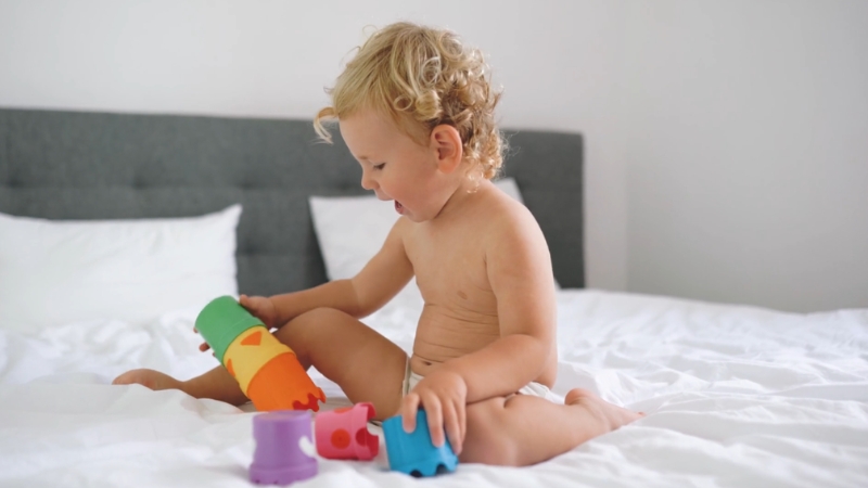 Baby sits and plays with toys while focusing attention on objects and actions
