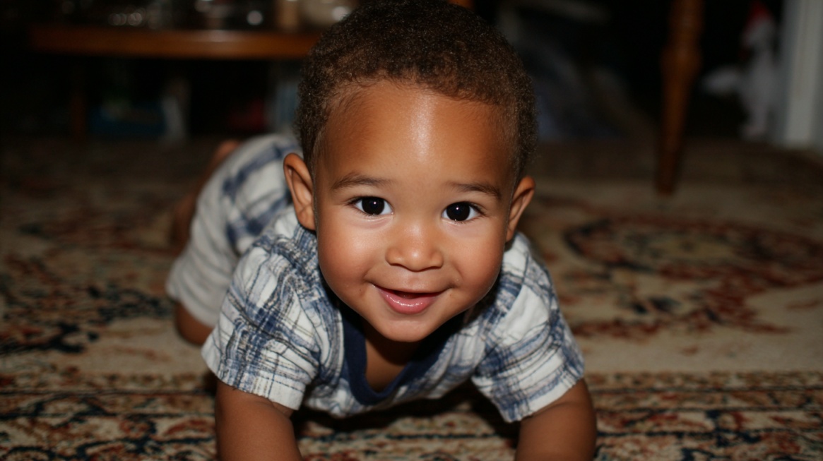 A smiling baby crawling on a patterned carpet, looking directly at the camera