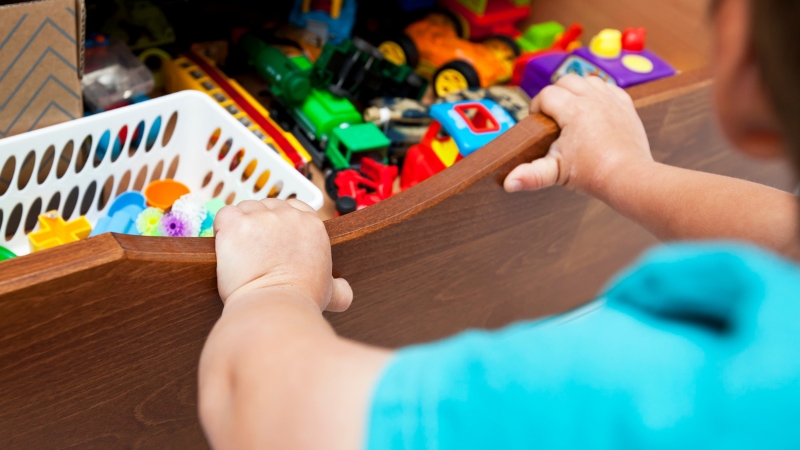 Toddler puts toys into a drawer during a simple daily routine to build independence and memory skills