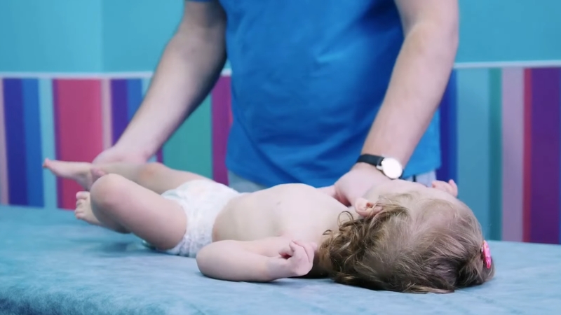 Doctor examines baby limb movement and posture to assess low muscle tone in infants