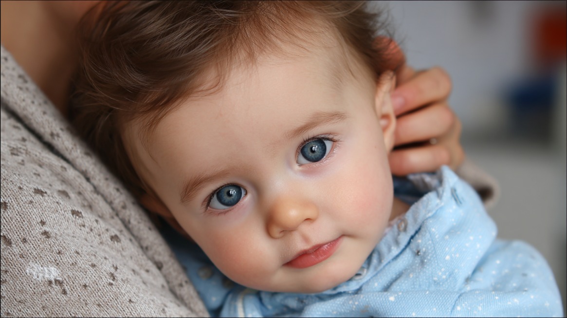 Baby with a slight head tilt resting against an adult, illustrating possible torticollis