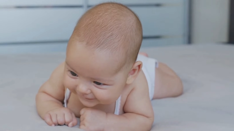 Baby on tummy with mild head lift showing low muscle tone in infants