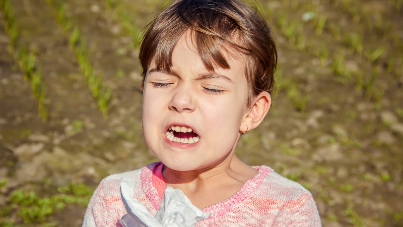 Child crying with eyes closed and face tense during sensory overload