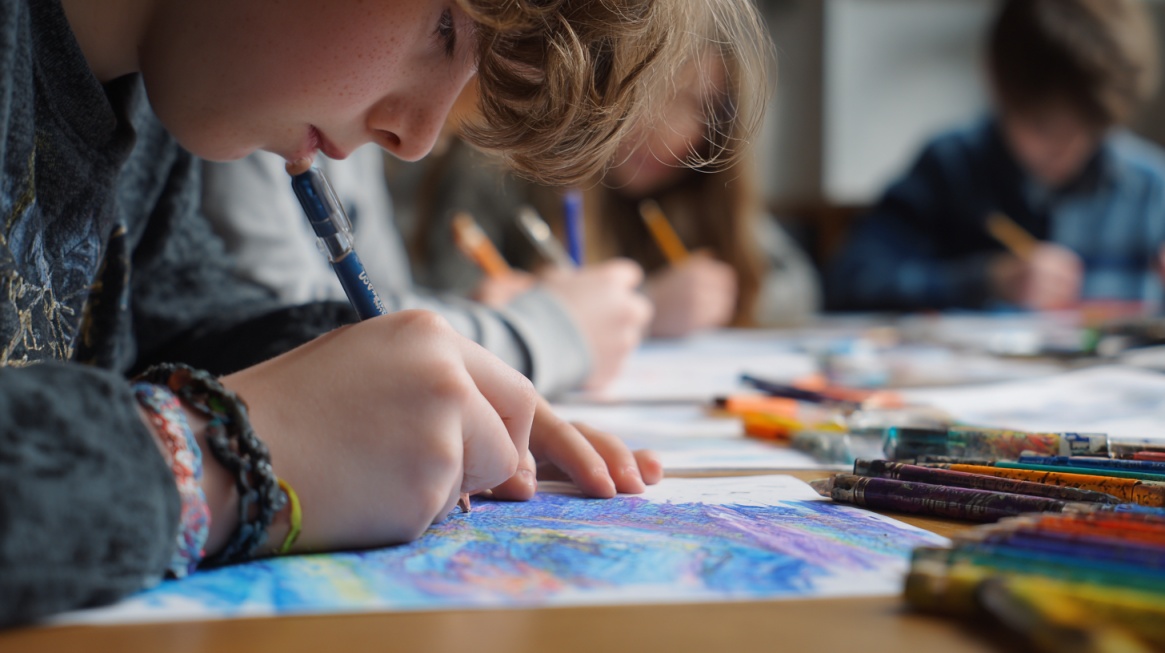 Close-up of children at a table using pencils and crayons to draw and write on paper